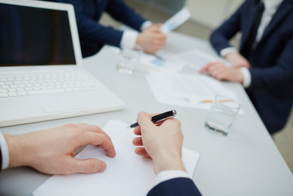 Mani che firmano e analizzano documenti relativi alla successione ereditaria e alla divisione dell’eredità tra gli eredi