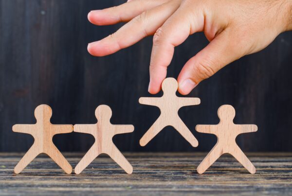 Mano che rimuove una figura umana di legno da un gruppo, simbolo dell’indegnità a succedere e dell’esclusione di un erede dalla successione.